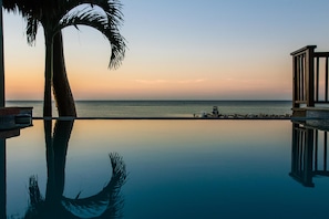 A tranquil infinity pool with a clear view of the ocean and a wooden deck.