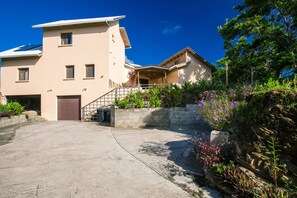 A two-story house with a garage, a covered porch, and a stone retaining wall with plants.
