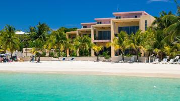 A beachfront hotel with multiple buildings, palm trees, and a sandy beach.