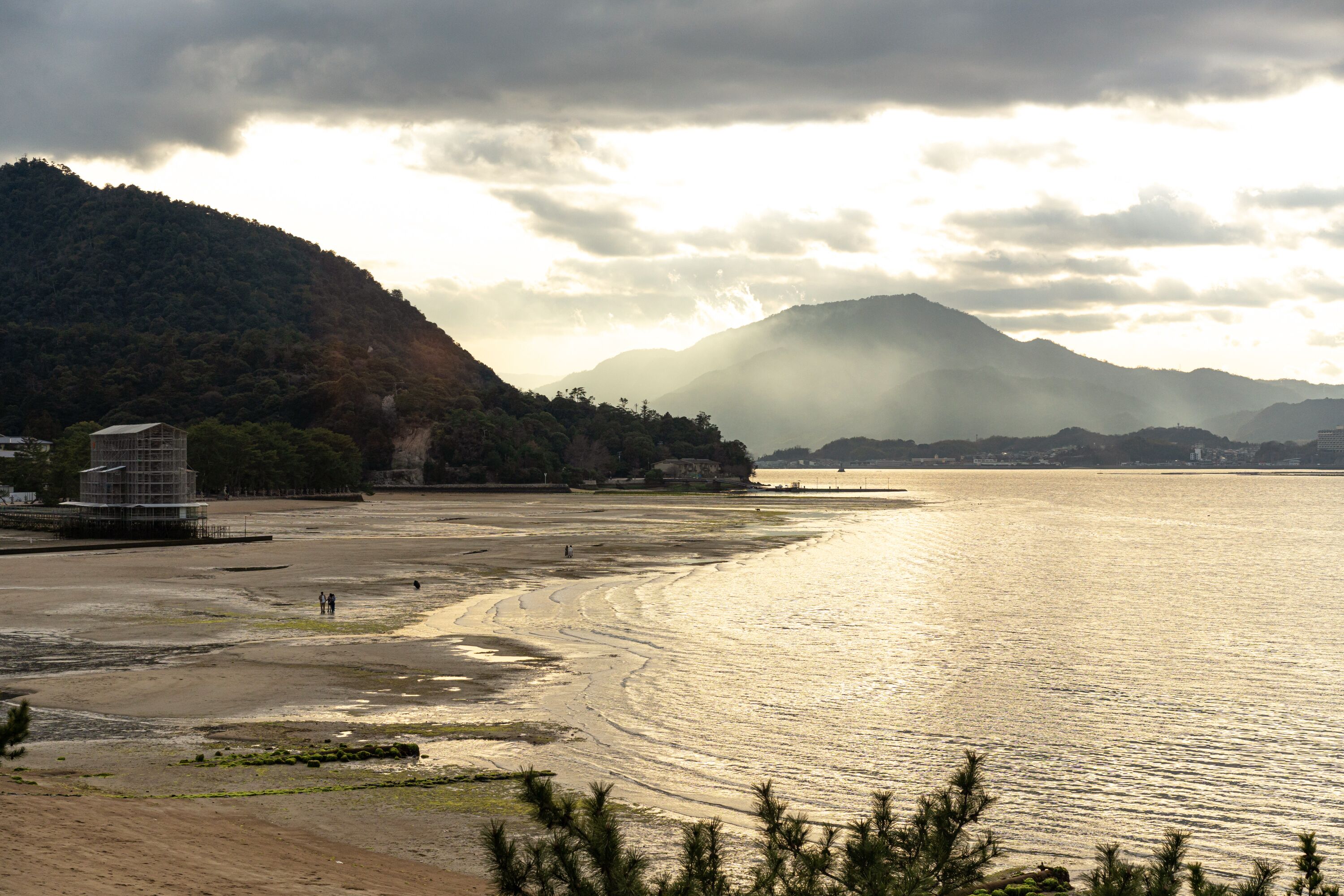 Un paisaje costero con una playa, una montaña y un edificio con andamios.