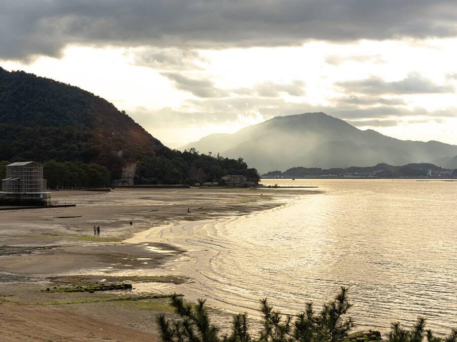 Un paisaje costero con una playa, una montaña y un edificio con andamios.