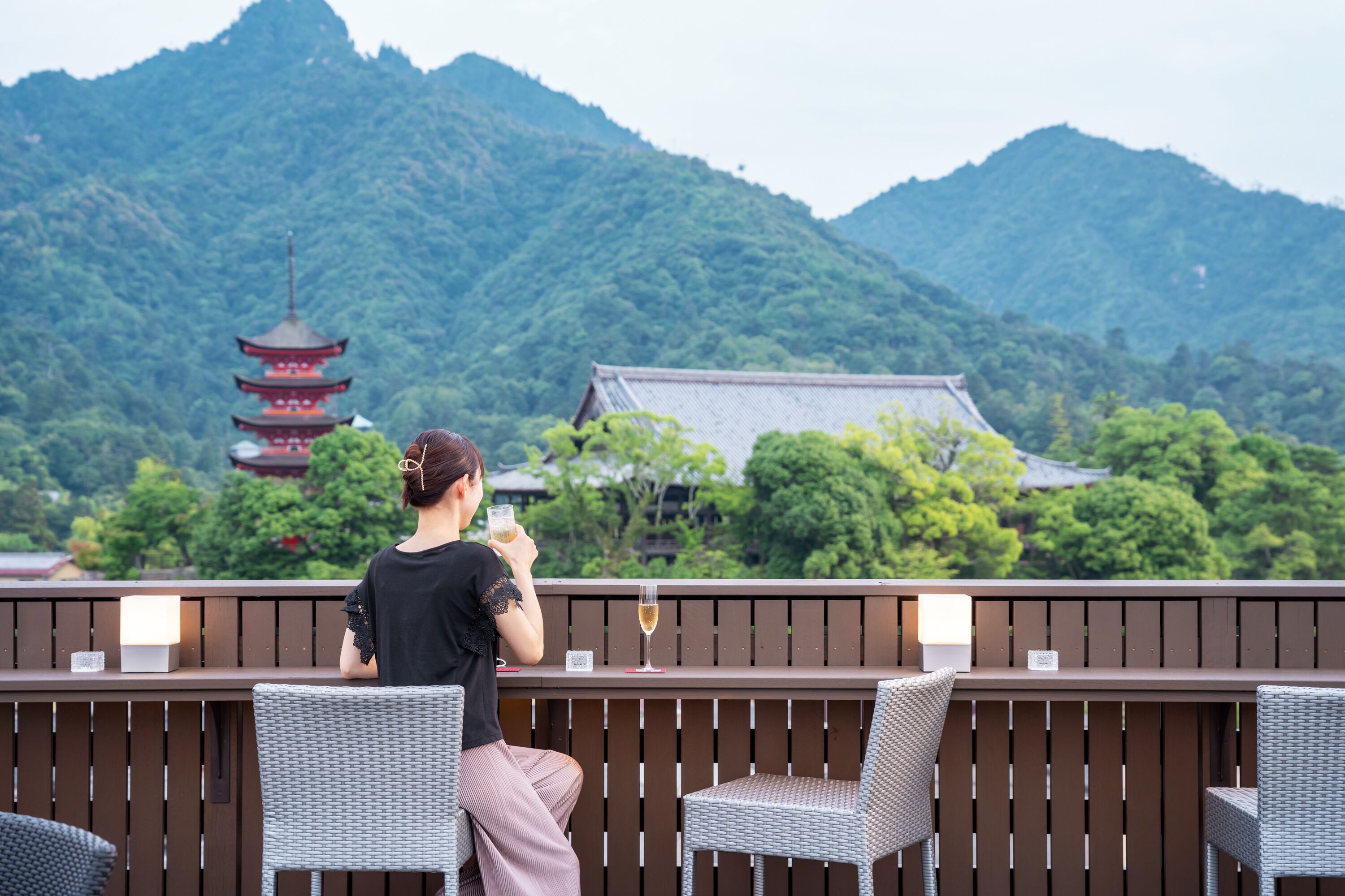 A person sitting at a wooden table with a view of a pagoda and mountains.