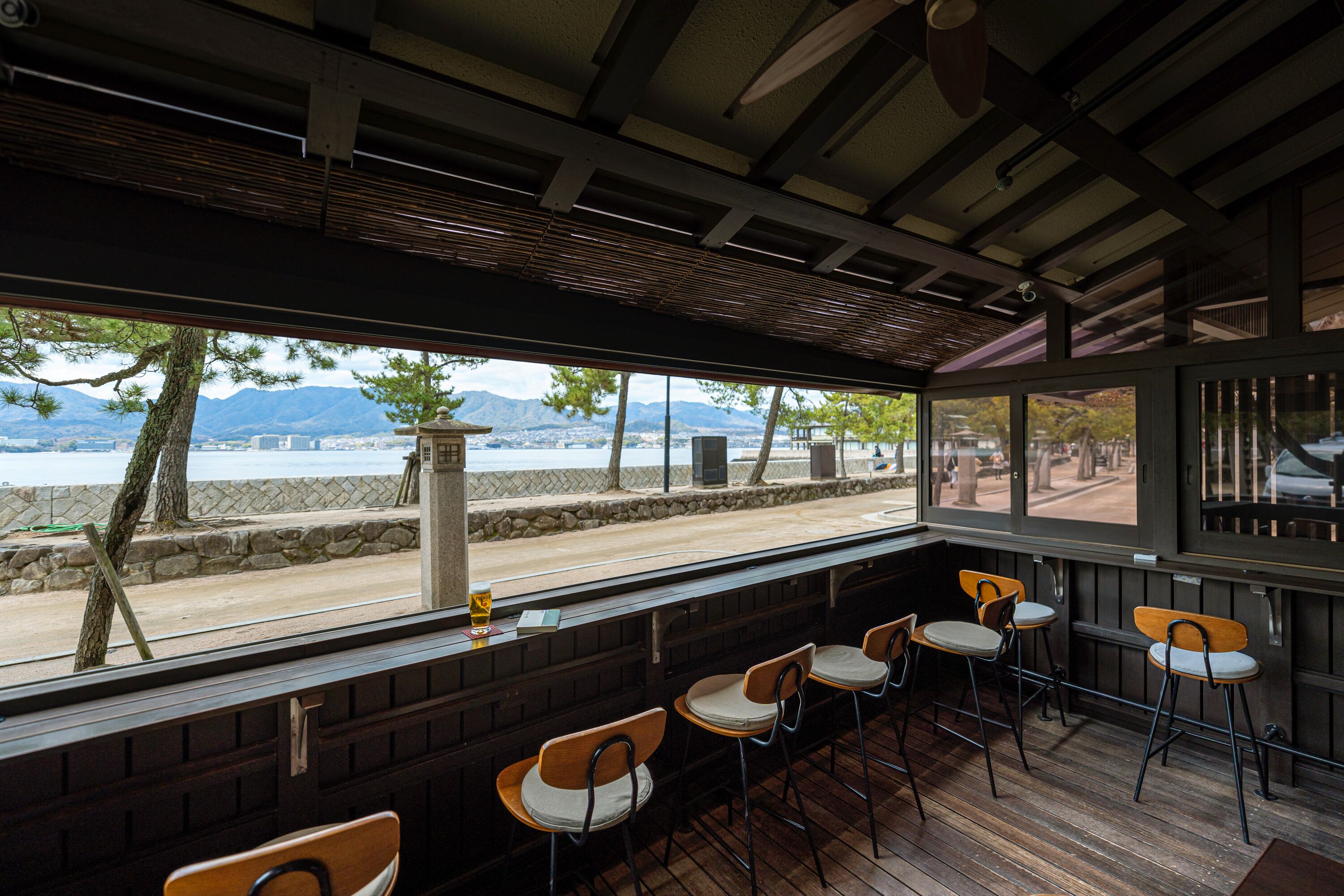 A restaurant with outdoor seating, a view of the beach, and mountains in the background.