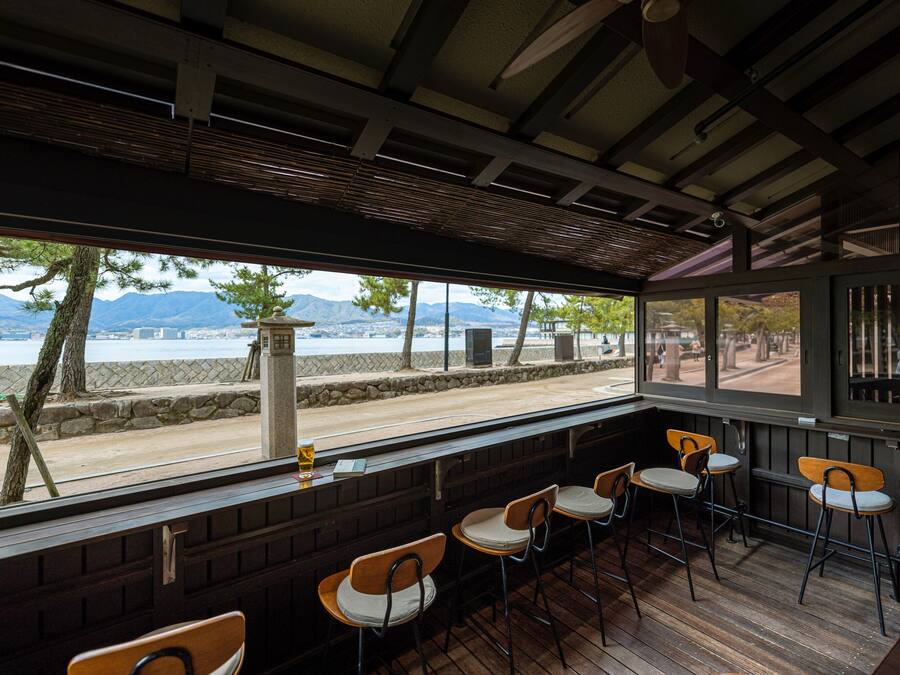 A restaurant with outdoor seating, a view of the beach, and mountains in the background.