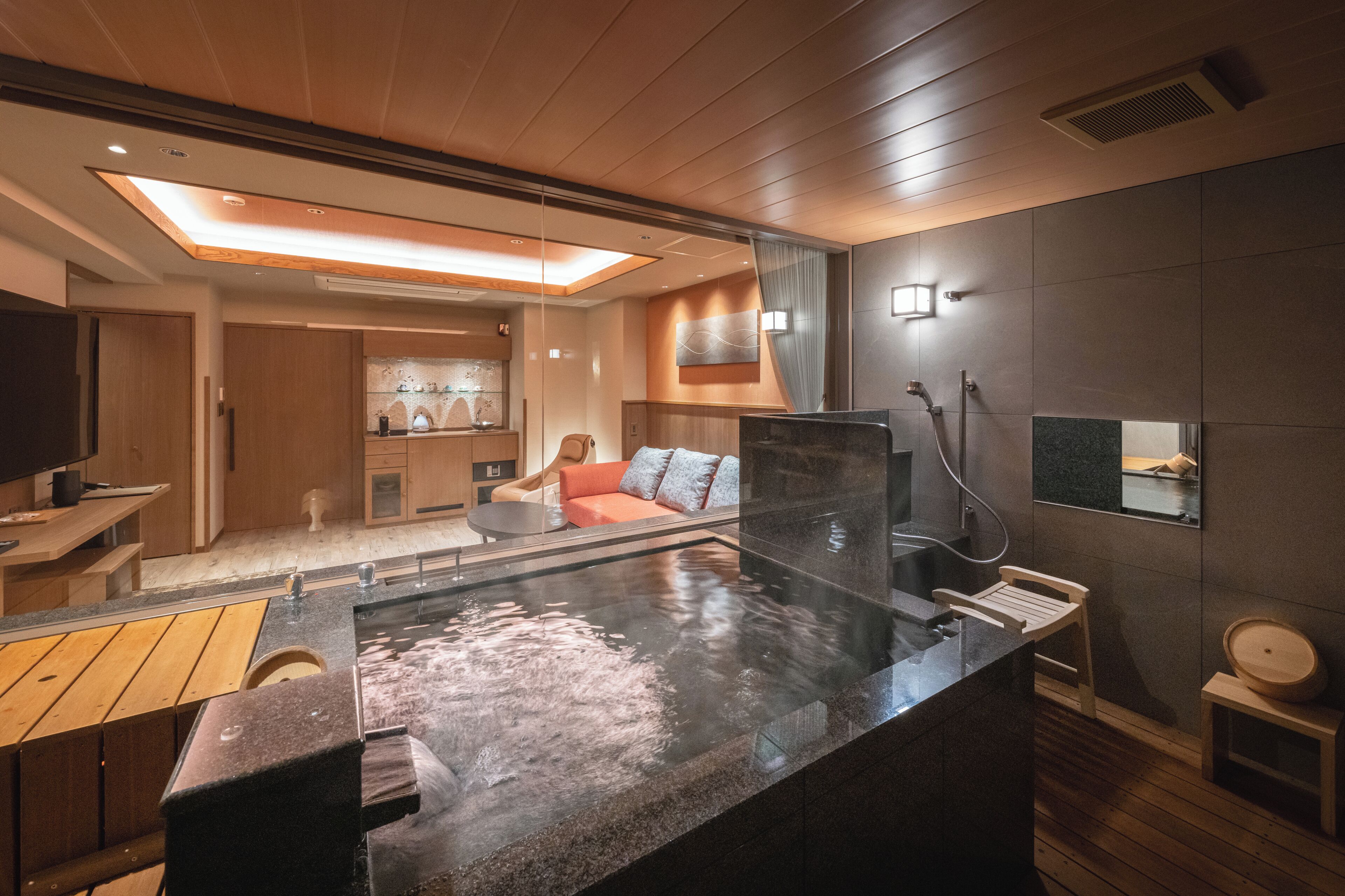 A modern spa area with a hot tub, wooden flooring, and a seating area with cushions.