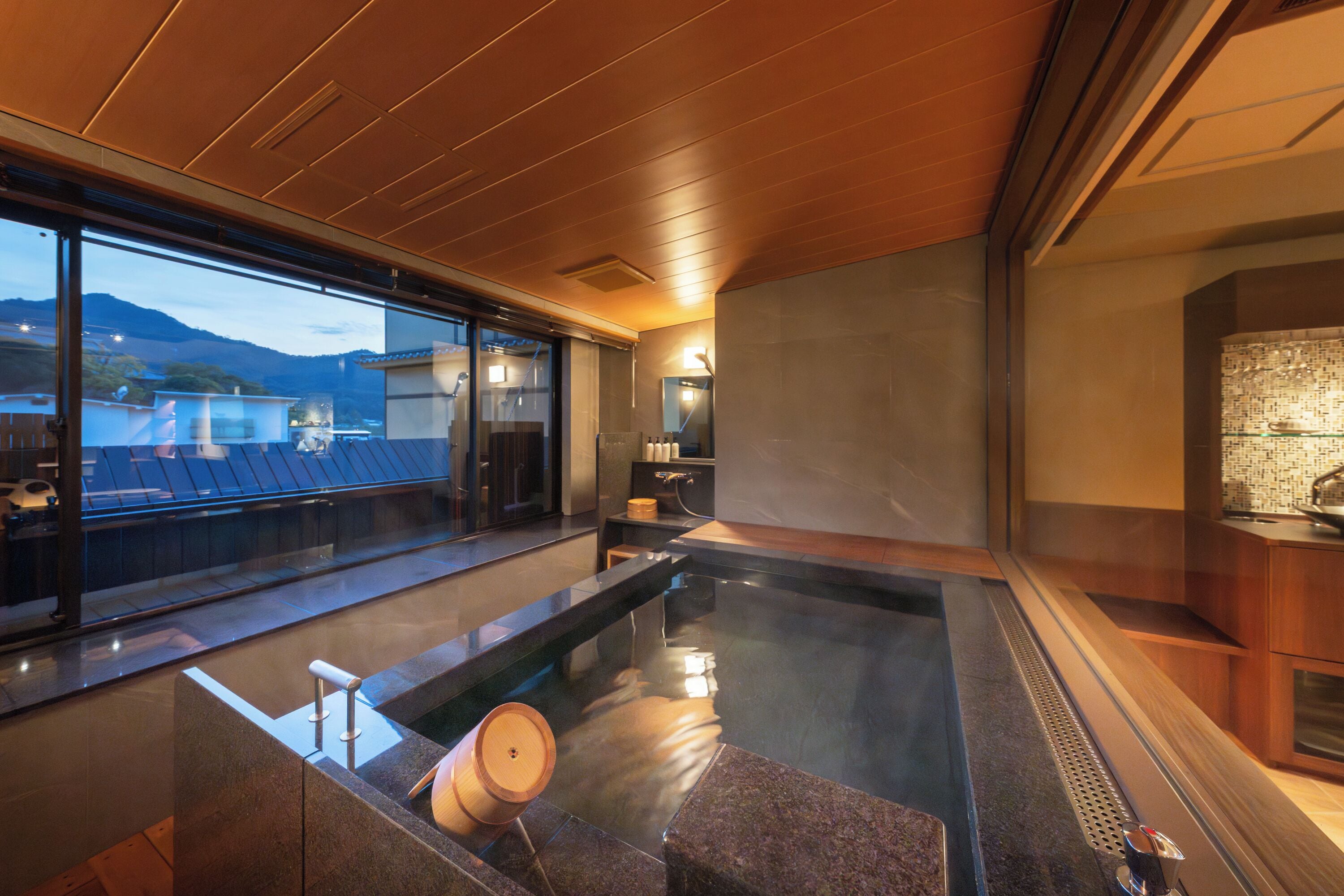 A modern spa area with a hot tub, wooden ceiling, and a view of the mountains.