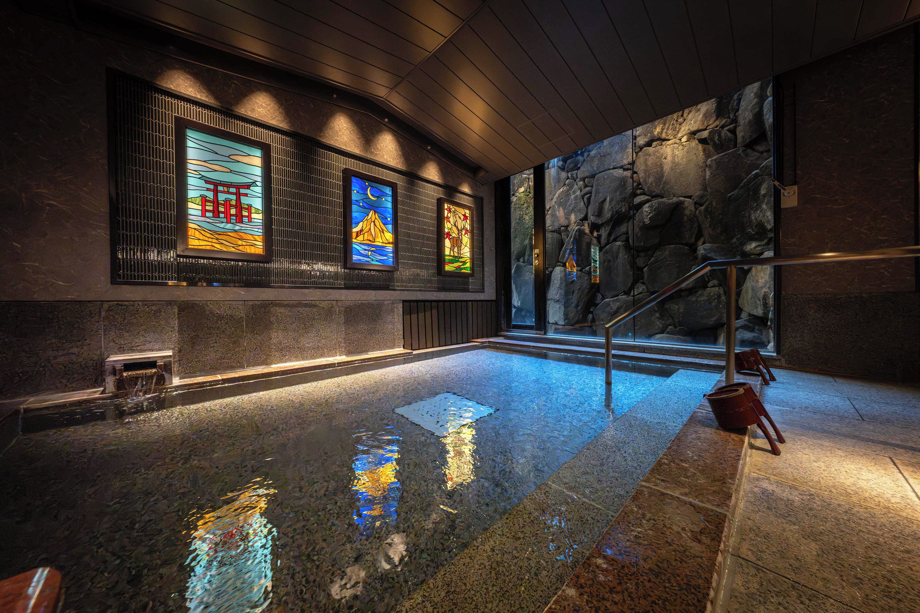 A spa area with a stone wall, a wooden ceiling, and a reflection pool.
