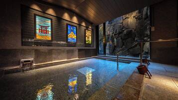 A spa area with a stone wall, a wooden ceiling, and a reflection pool.