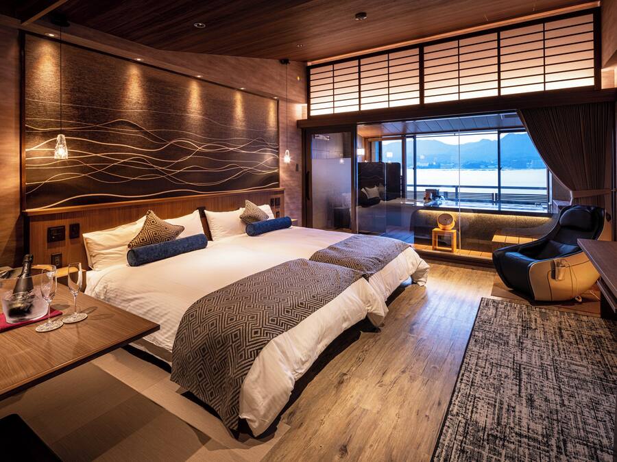 Ein modernes Hotelzimmer mit einem großen Bett, einer Sitzecke mit Blick und einer Holzzieldecke.