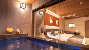 A modern hotel room with a large bed, a small desk, and a hot tub. - Miyajima Kinsuikan (Hatsukaichi)