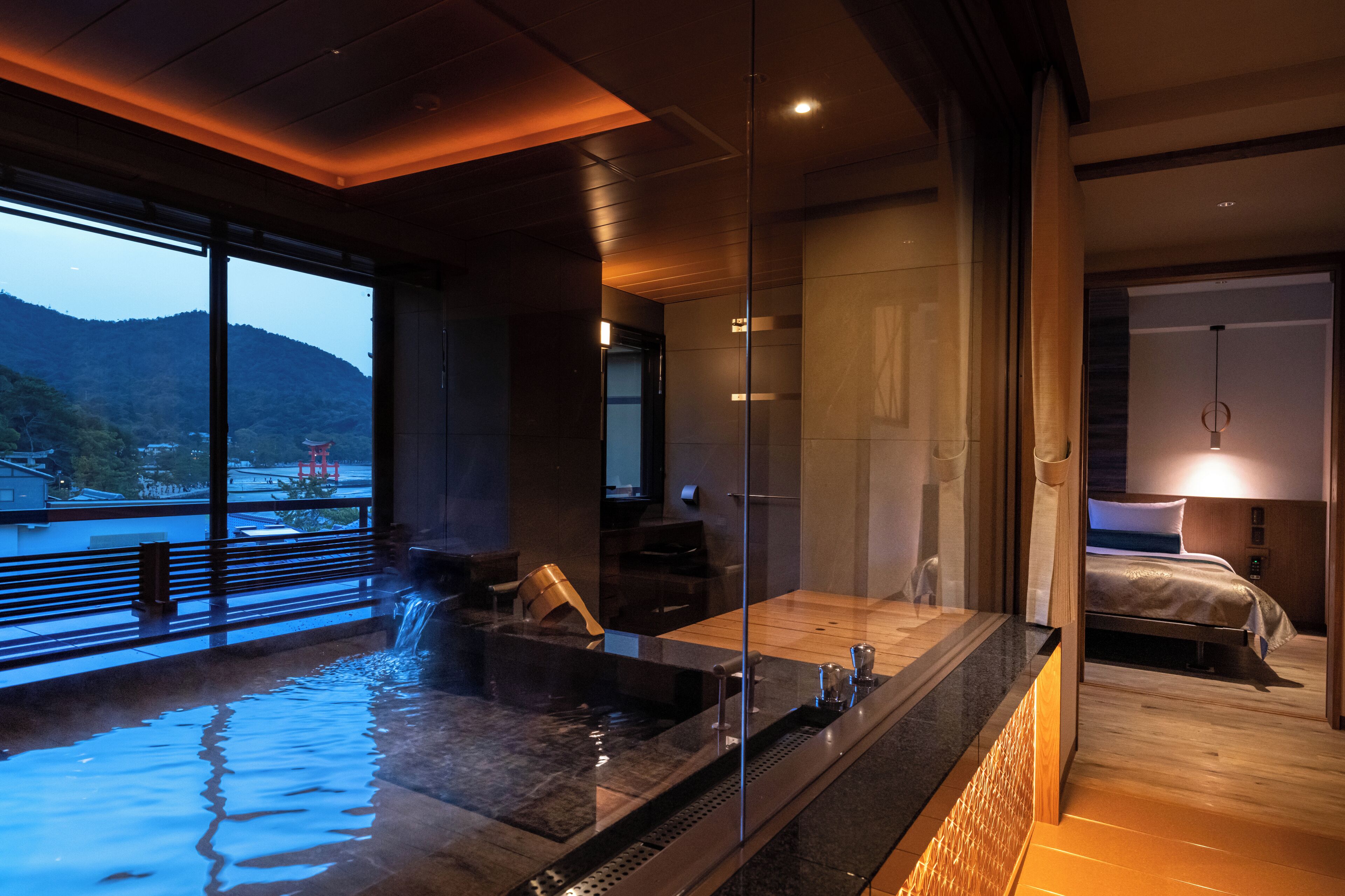 A modern spa area with a hot tub, a wooden floor, and a view of a mountain.