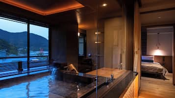 A modern spa area with a hot tub, a wooden floor, and a view of a mountain.