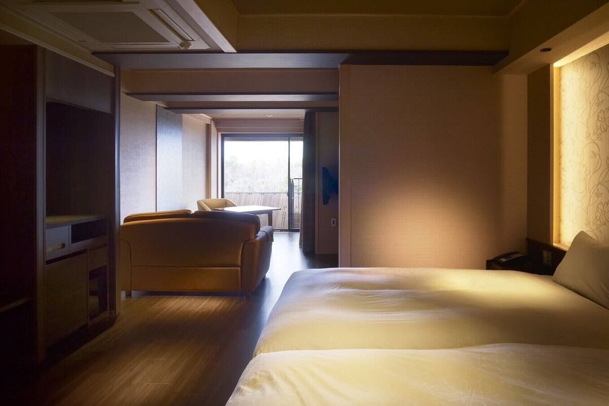 Ein Hotelzimmer mit Bett, Sofa, Schreibtisch und Blick ins Freie.
