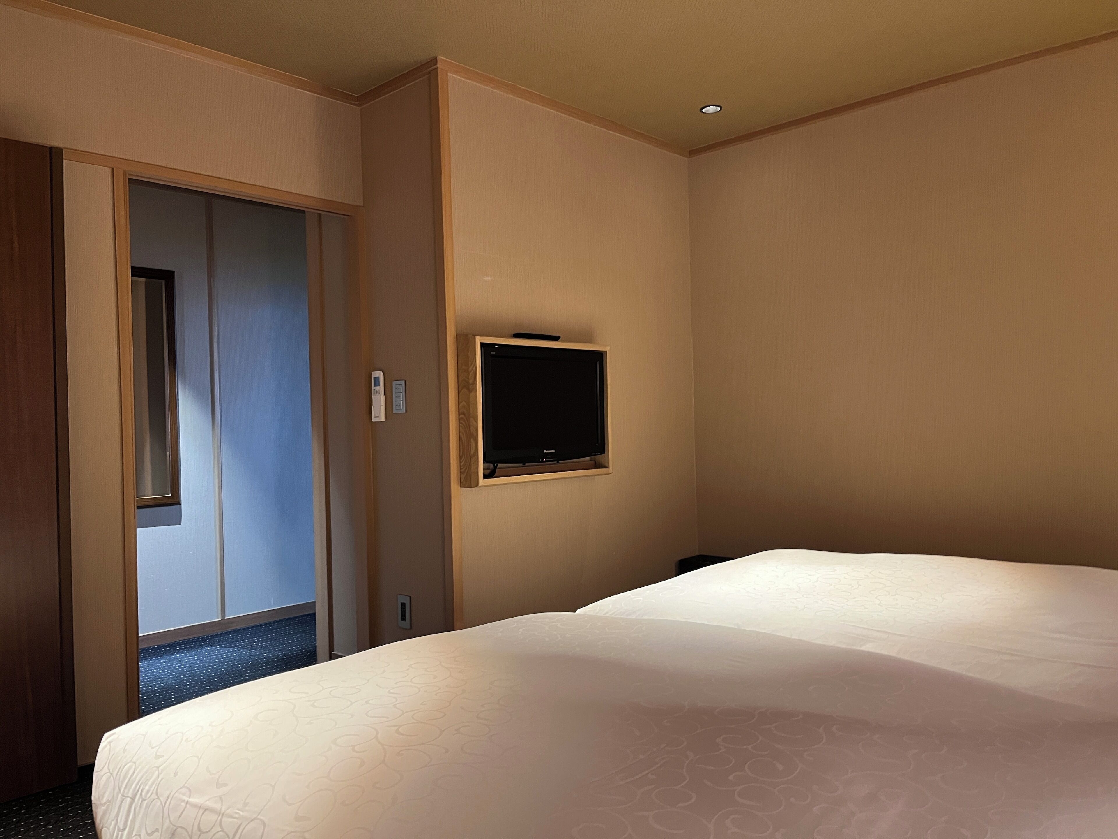 Una habitación de hotel con una cama, un armario y un televisor montado en la pared.
