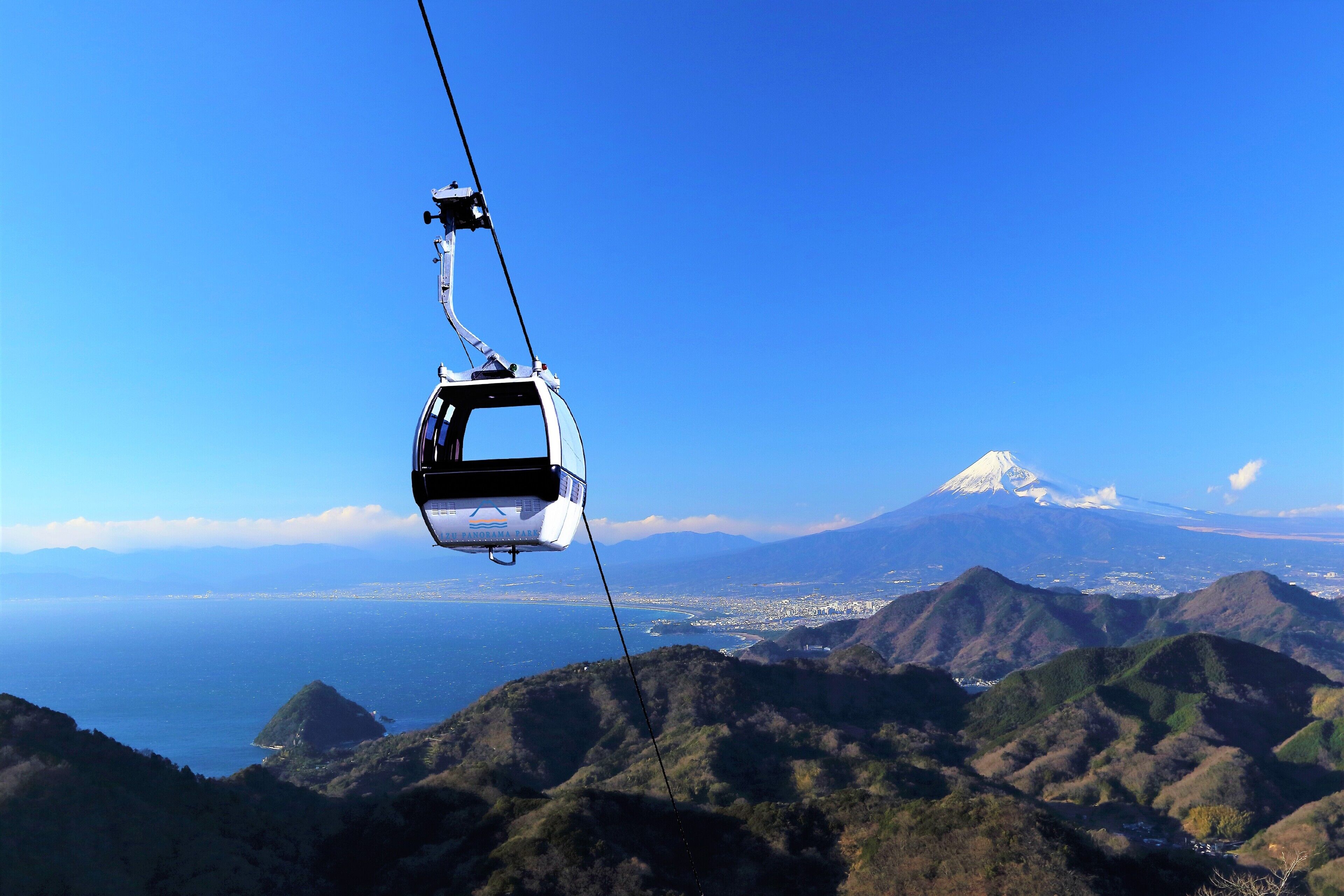 Un teleférico ofrece vistas despejadas de una montaña y una ciudad costera en la falda.