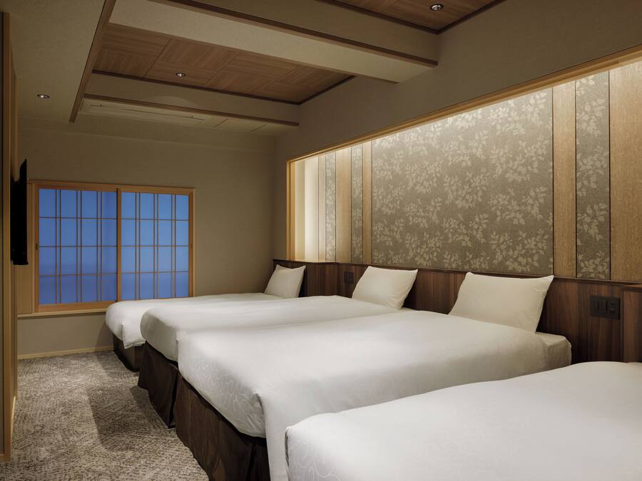 A hotel room with two beds, a large window, and a wooden ceiling.