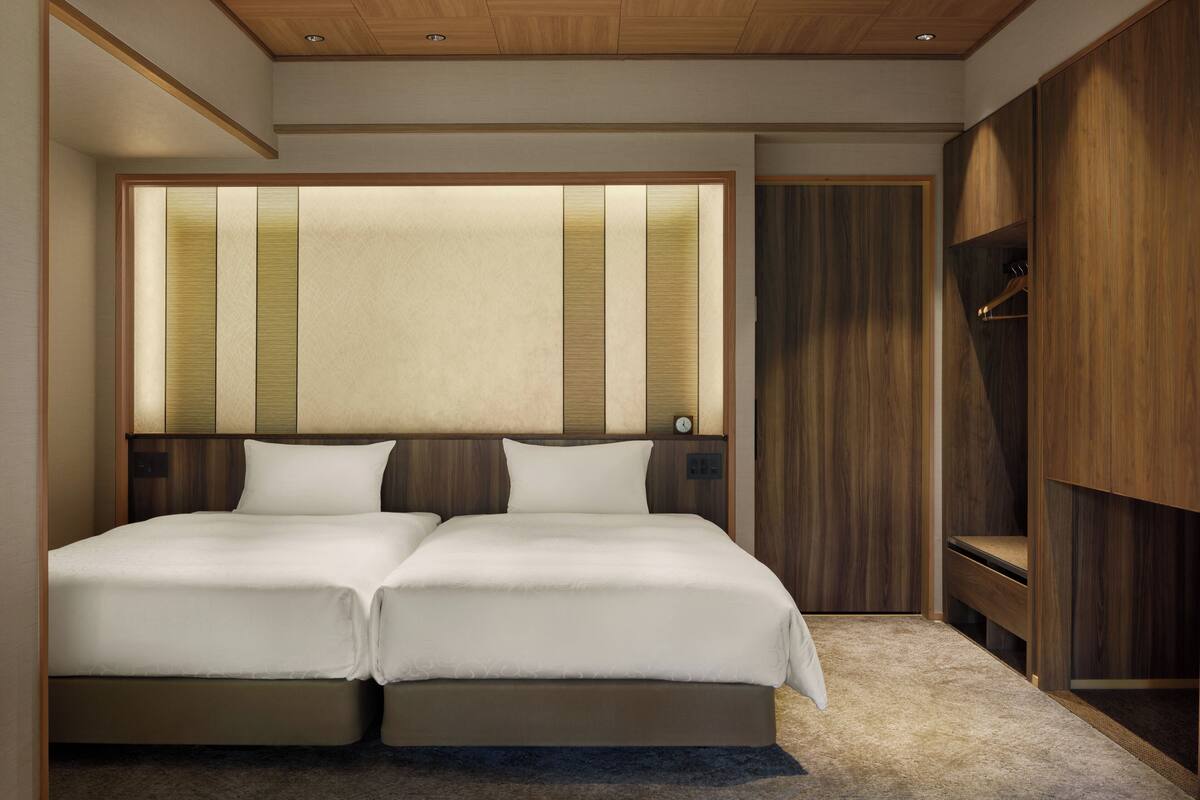 Ein Doppelbett mit Holz-Kopfteil und einer Wandverkleidung in neutralen Farbtönen.