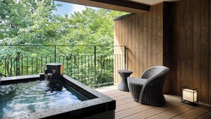 A wooden deck with a hot tub, wicker chairs, and a lantern.