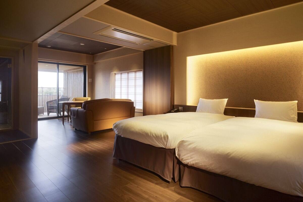 Ein Hotelzimmer mit einem großen Bett, einer Sitzecke, einem Essbereich und Blick ins Freie.