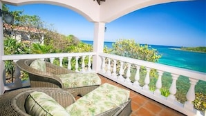 A covered balcony with wicker furniture and a view of the ocean. - Coral Vista 4 3 bedroom option (Roatan)