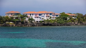 A beachfront property with multiple buildings, a rocky shoreline, and clear turquoise water. - Coral Vista 5 (Roatan)
