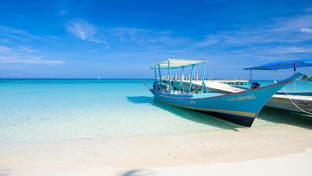 A boat named 'CaptBrooks' docked on a sandy beach with clear turquoise water. - Coral Vista 5 (Roatan)