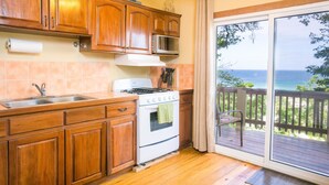 Una cocina con armarios de madera, un lavamanos de acero inoxidable, una estufa y vistas al océano a través de un ventanal corredero.