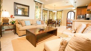 A living room with a sofa, coffee table, and dining area with chairs and a table.