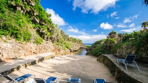 A beach with lounge chairs and a narrow water channel.