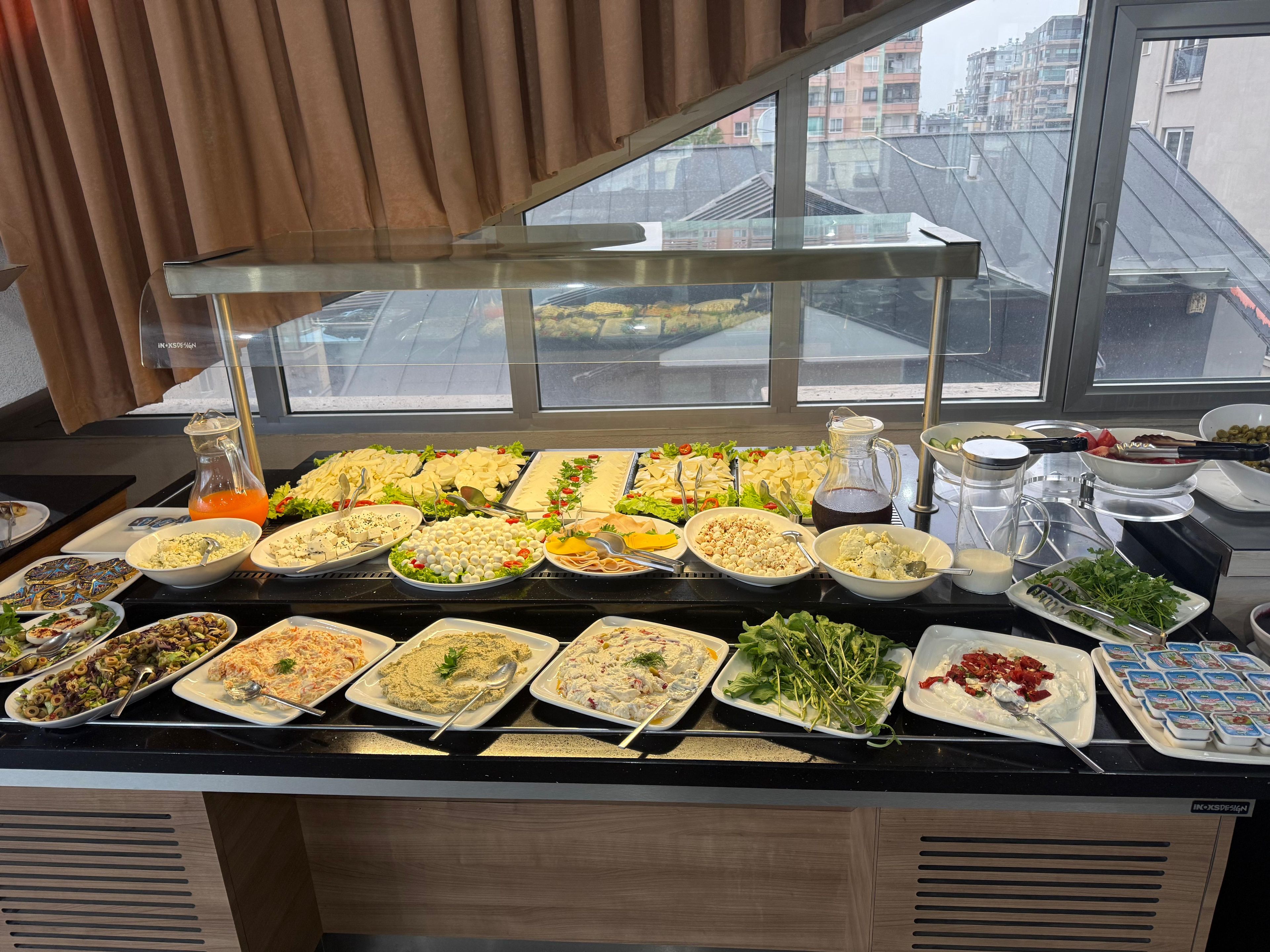 Un buffet proposant divers plats et une carafe de jus d’orange.