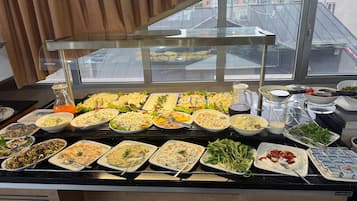 Un buffet proposant divers plats et une carafe de jus d’orange.