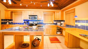 Une cuisine avec des meubles en bois, un îlot central et un ventilateur de plafond.