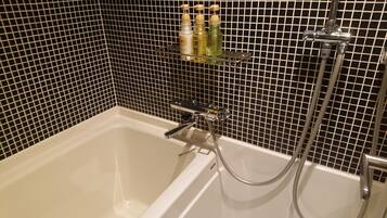 Ein Badezimmer mit Badewanne, Dusche und Ablage für Toilettenartikel.