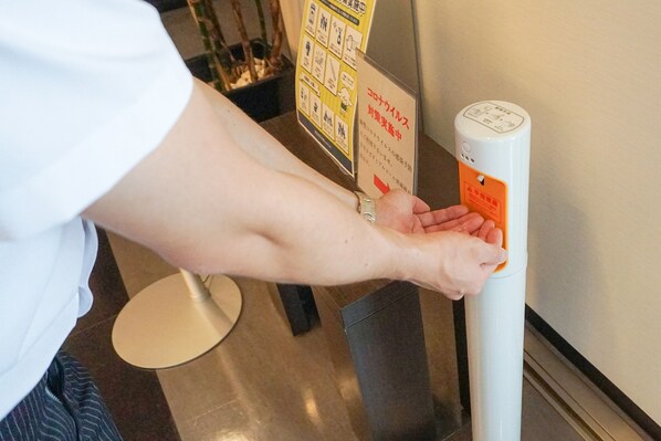 Une personne utilise un distributeur de gel hydroalcoolique.