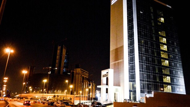 A modern hotel with a prominent vertical structure and a glass facade. - Executives Hotel Kafd (Riyadh)