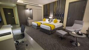 A hotel room with two beds, a desk, a chair, and a small table. - Executives Hotel Kafd (Riyadh)