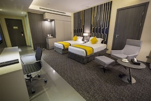 Une chambre d’hôtel avec deux lits, un bureau, une chaise et une petite table.