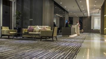 A modern lobby with a sofa set, a coffee table, and a reception desk.