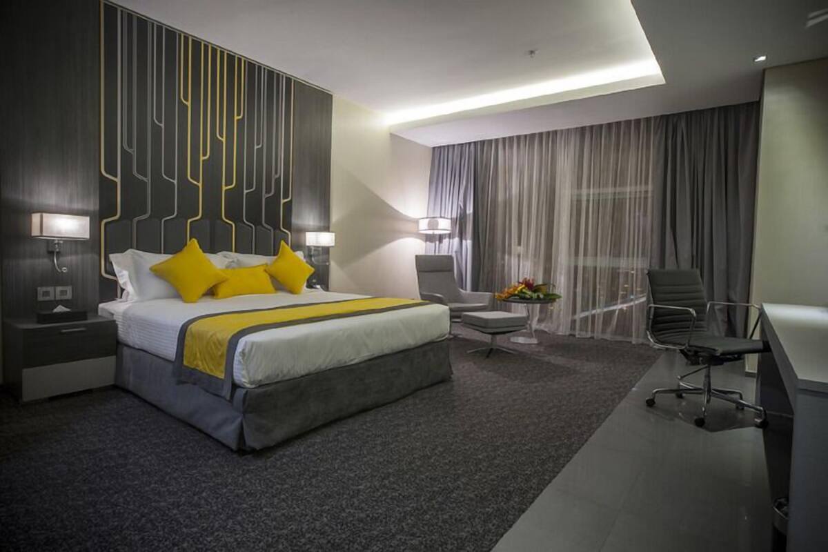 A modern hotel room with a large bed, a desk, and a chair.