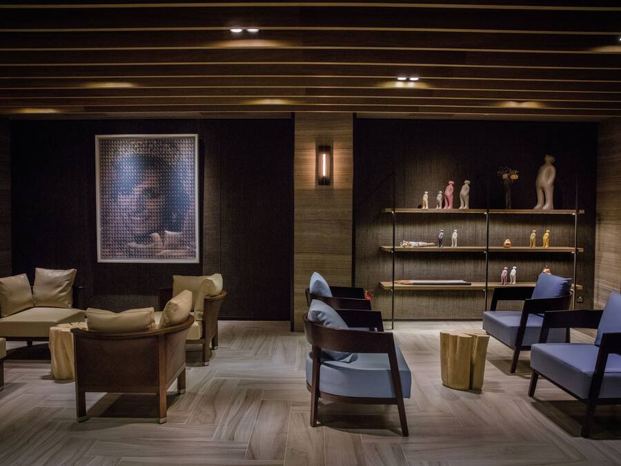 Un salón moderno con sofás de cuero, una mesa de centro de madera y una estantería con objetos decorativos.