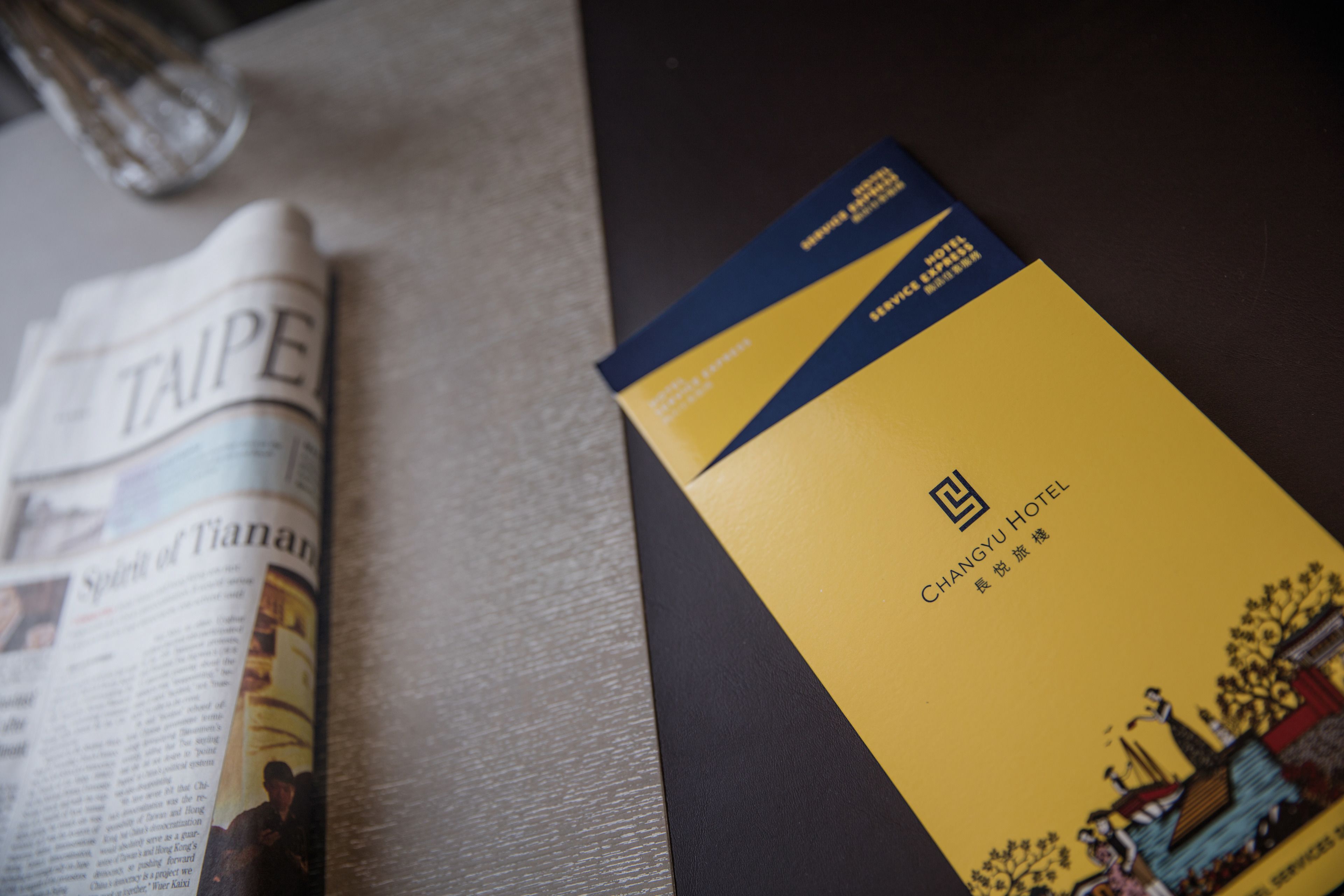 A newspaper with the headline "Spirit of Tiananmen" and a brochure for Changyu Hotel.