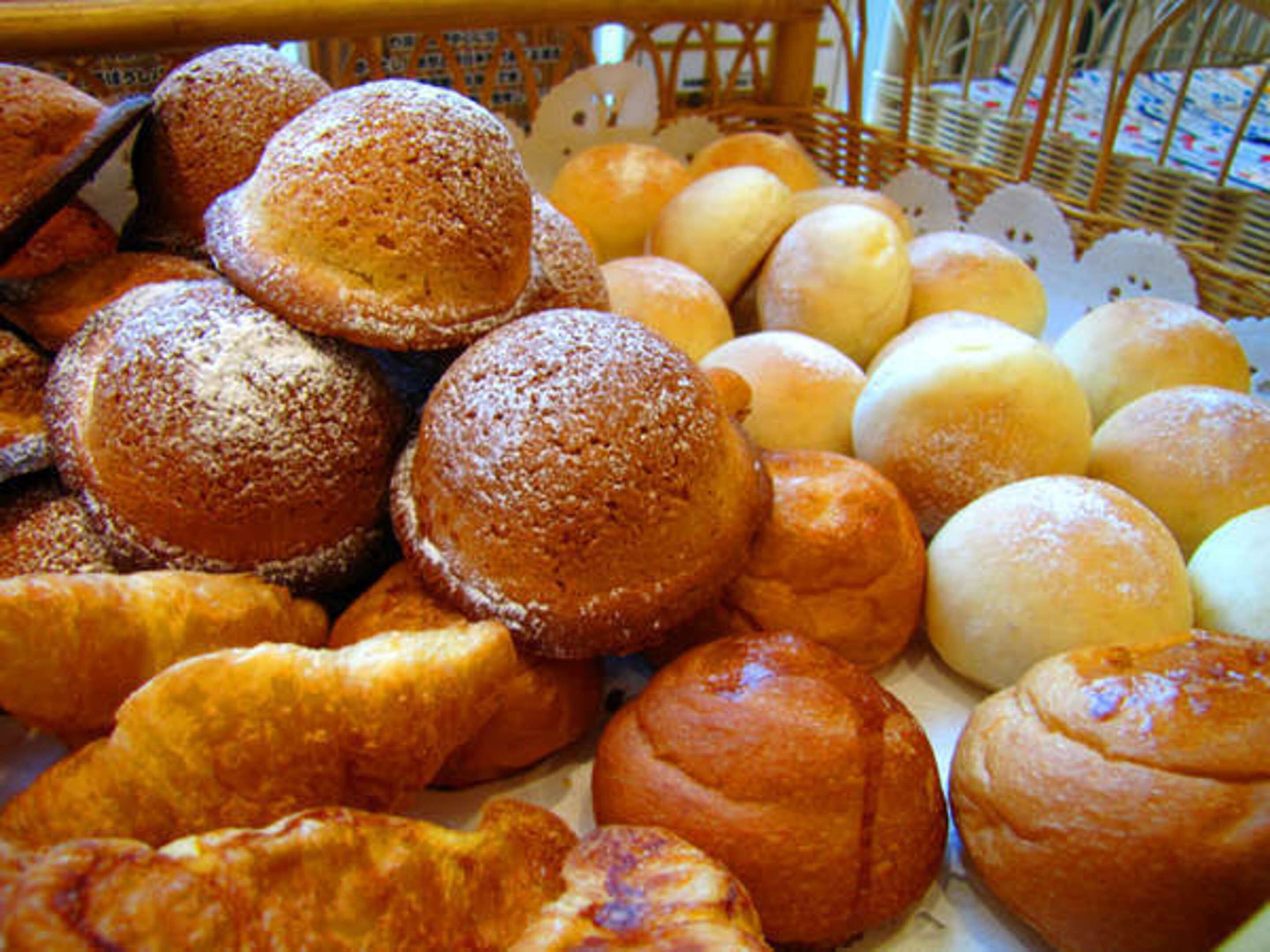 Una cesta repleta de panes y pasteles varios.