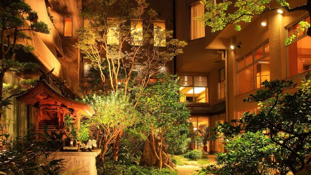 A traditional Japanese-style courtyard with a wooden torii gate, stone lanterns, and lush greenery. - Jyoseikan (Kochi)