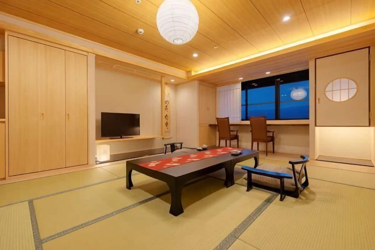 A traditional Japanese room with tatami flooring, a low table, and a television.