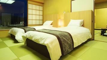 Habitación de hotel con dos camas, un ventanal grande y una puerta corrediza tradicional japonesa.