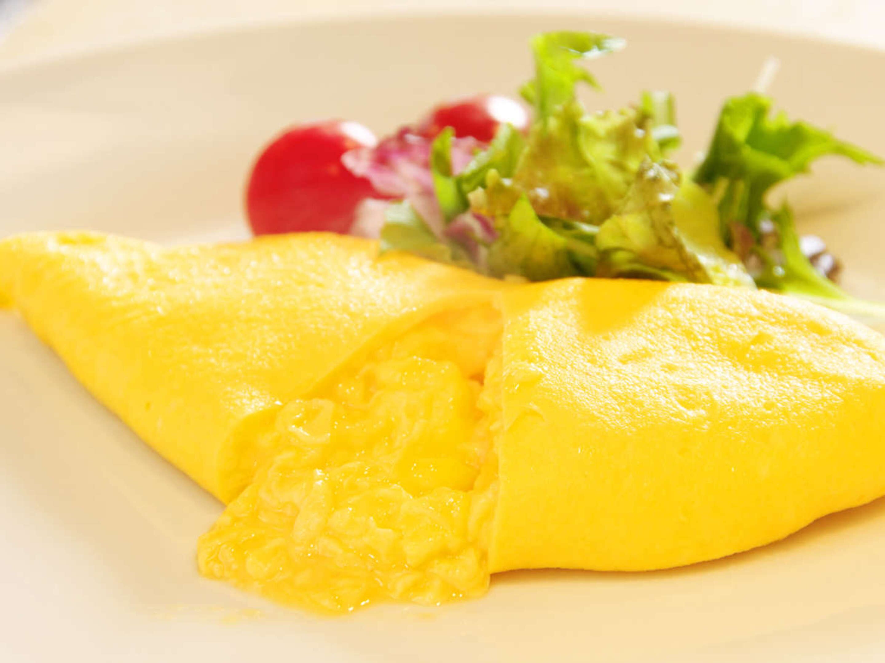 Un plat amb truita doblegada, un préssec i una amanida al costat.