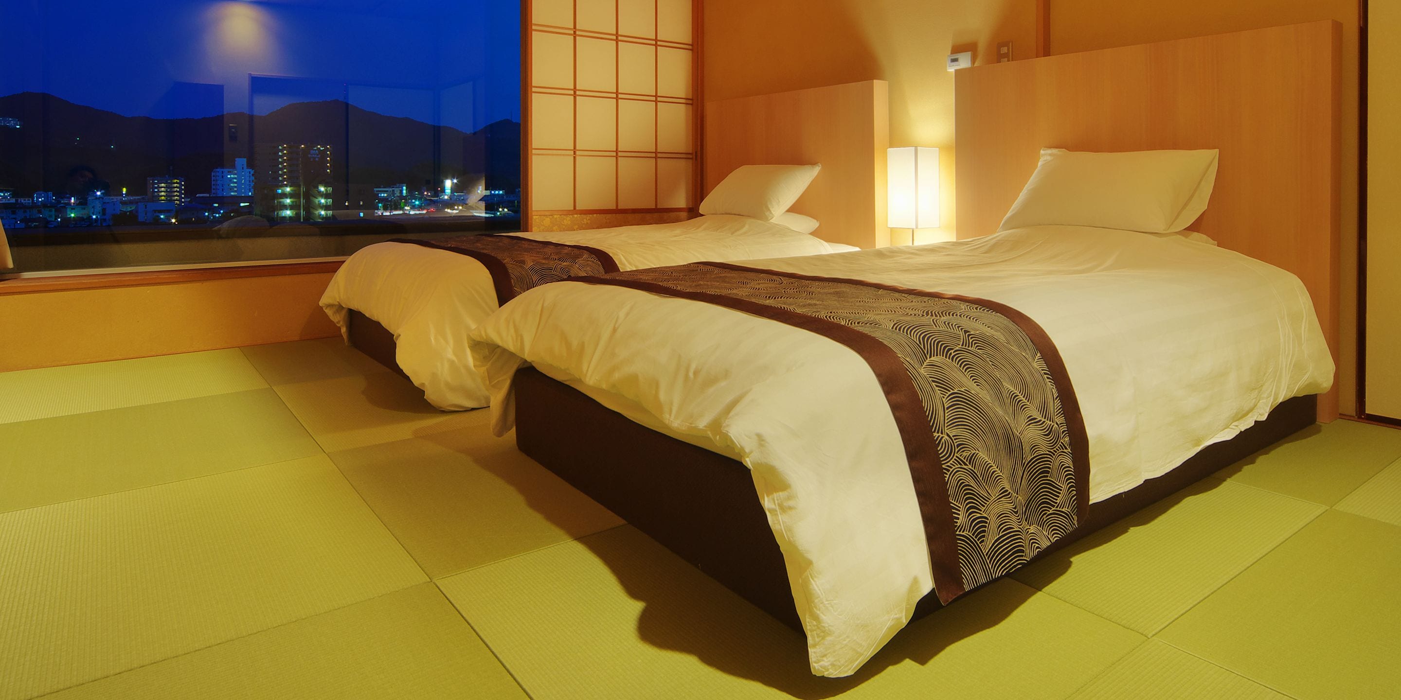 A hotel room with two beds, a city view, and a traditional Japanese-style sliding door.