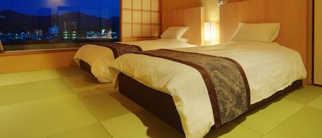 A hotel room with two beds, a city view, and a traditional Japanese-style sliding door.