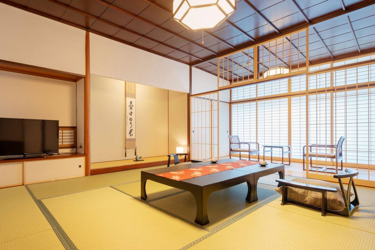A traditional Japanese room with tatami flooring, a low table, and sliding doors.