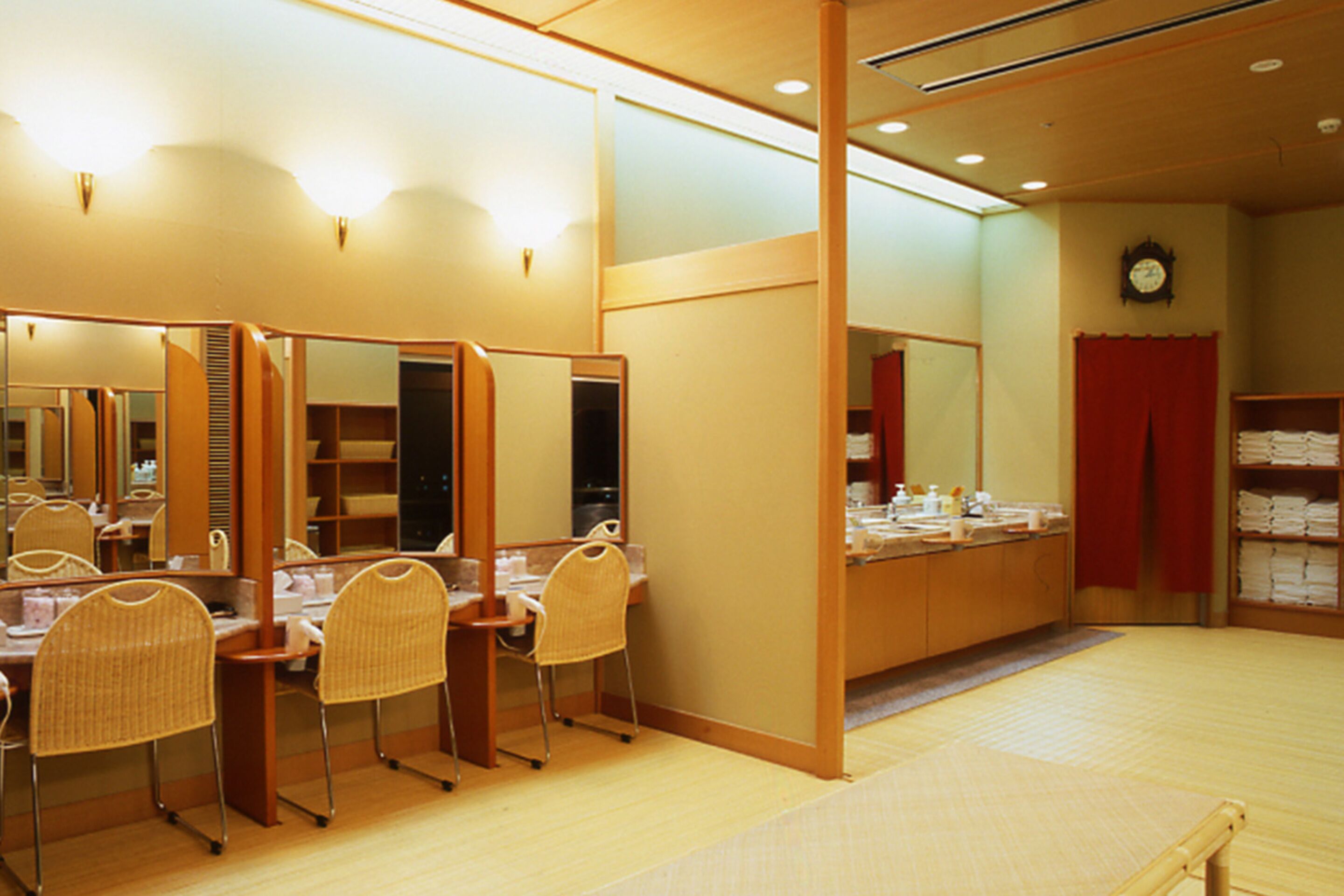 A room with multiple mirrors, wooden furniture, and a clock on the wall.